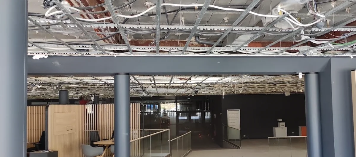La misma superficie en fase de estructura metálica suspendida, perfilería y cables vistos