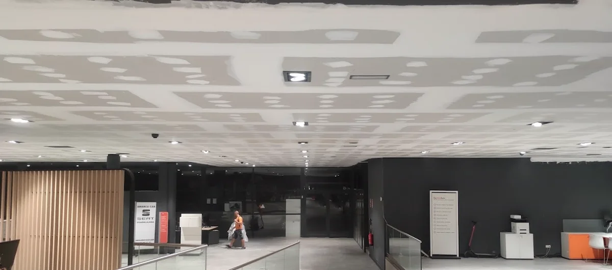 Gran superficie comercial con falso techo de pladur terminado, encintado e iluminación encendida realizado por DCC