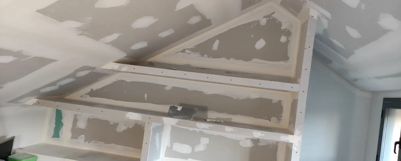 Mueble a medida de pladur con hornacinas y baldas en buhardilla inclinada realizado por DCC